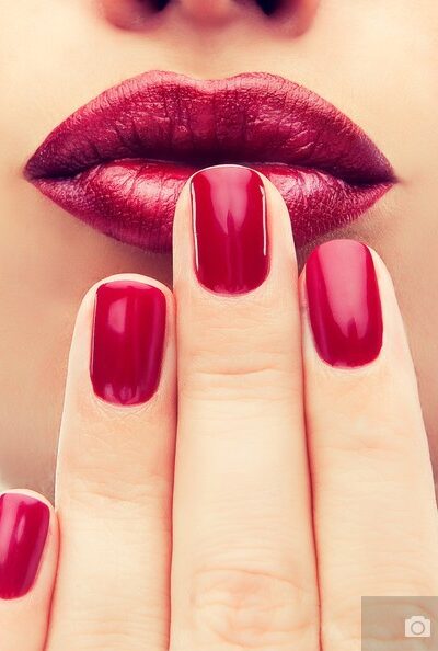 Beautiful model  shows red  manicure on nails. Red lips .Luxury